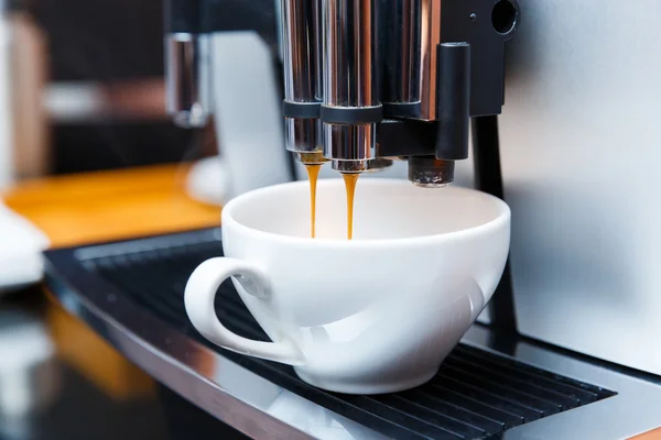 coffee machine pouring coffee into white glass cup