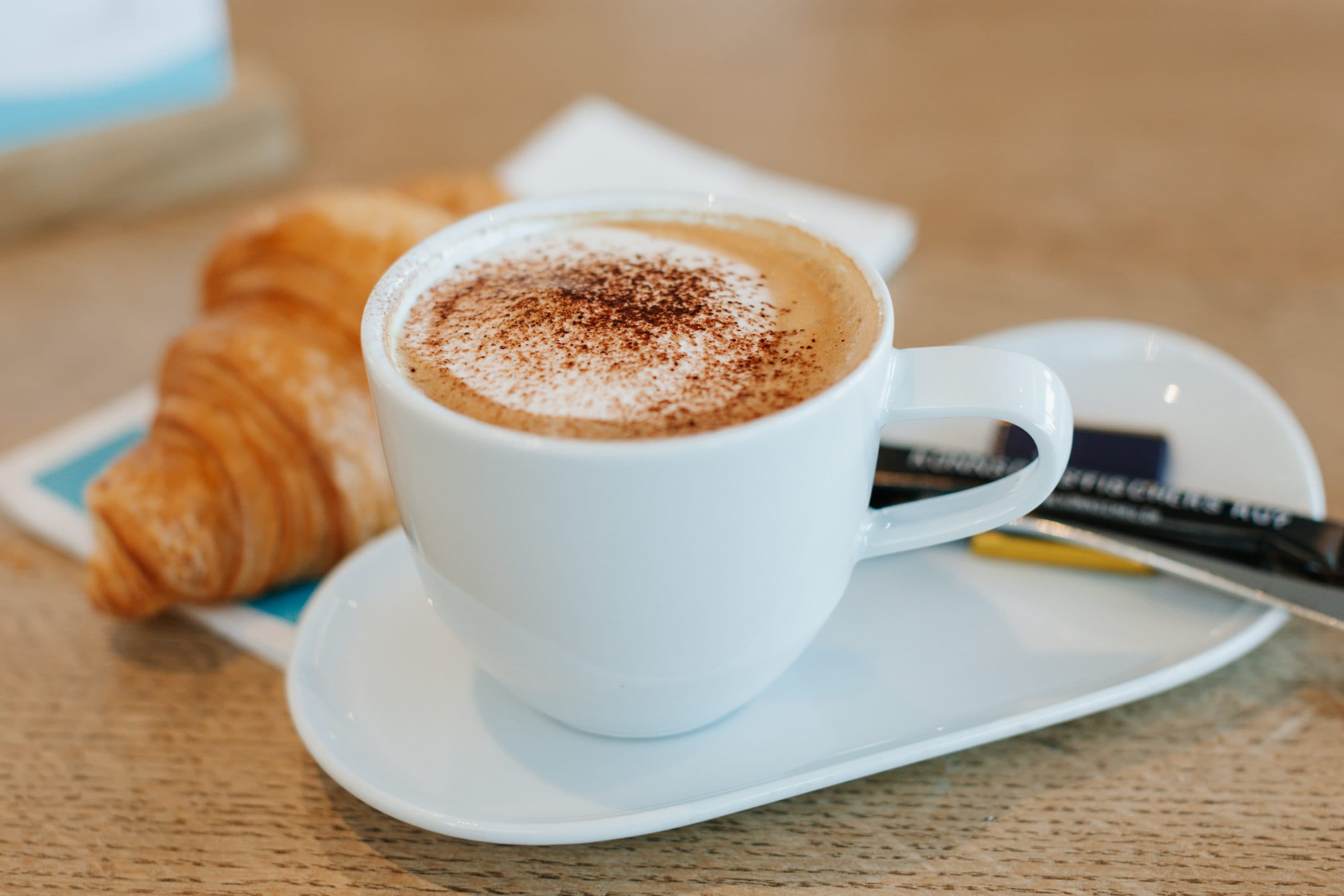 cup of coffee in white glass and croissant